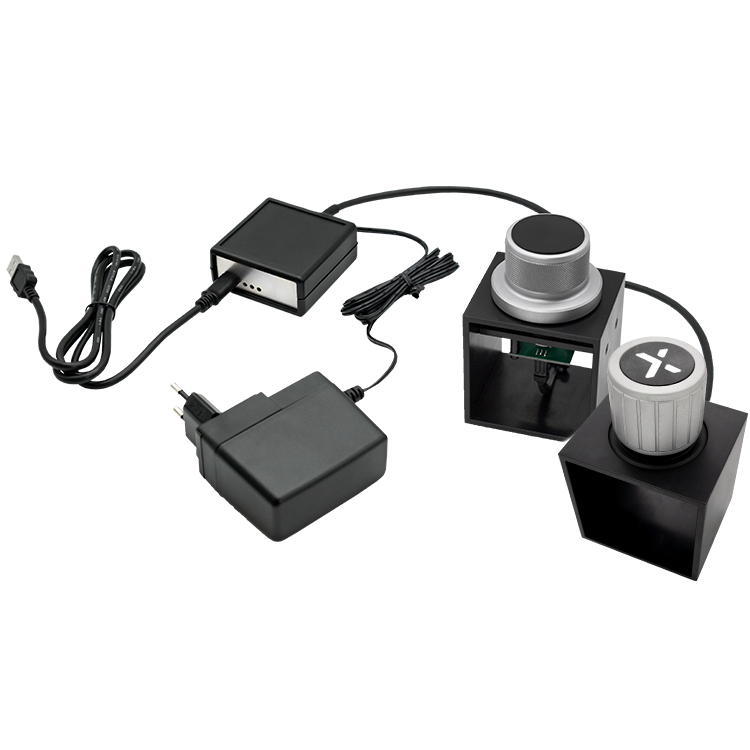 The image shows a HAPTICORE Eval Kit Combi Bundle consisting of a HAPTICORE 34-P001X3 and HAPTICORE 40-P001X1 Eval Kit as well as a HAPTICORE Control Unit Pro, including a 12 V power supply and USB-C connection cable.